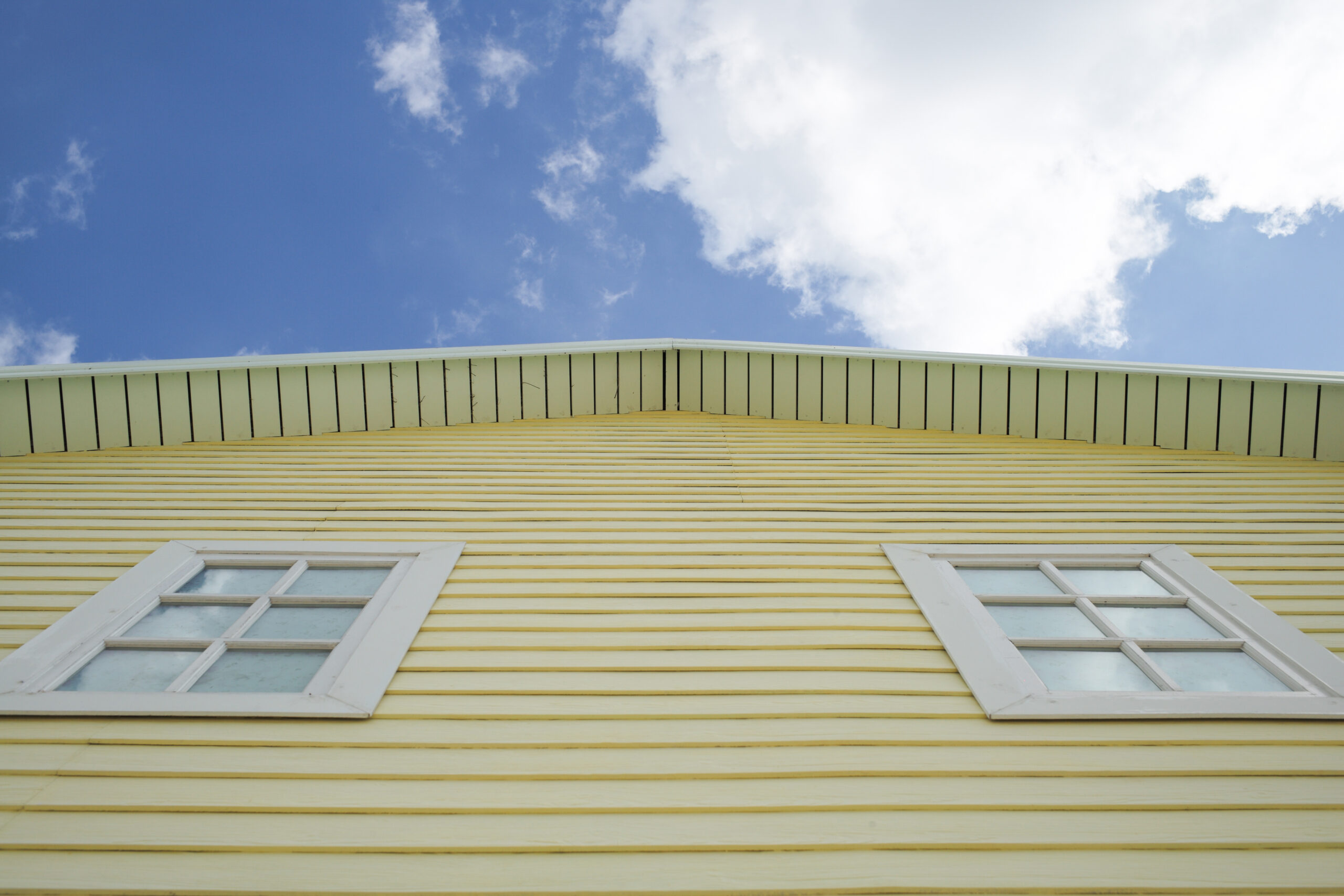 Exterior of yellow house with sky and cloud in low angle view GAF Roof Replacement in Timonium MD